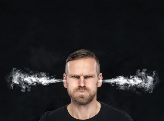 angry man with smoke or fume coming out from his ears on dark background.